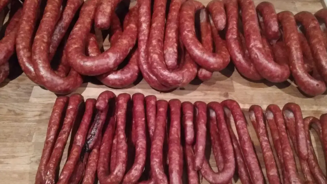 Dwie linie świeżo uwędzonej, prawdziwej wiejskiej kiełbasy, gotowe do podania. Przepis na domową kiełbasę jest w zasięgu ręki!