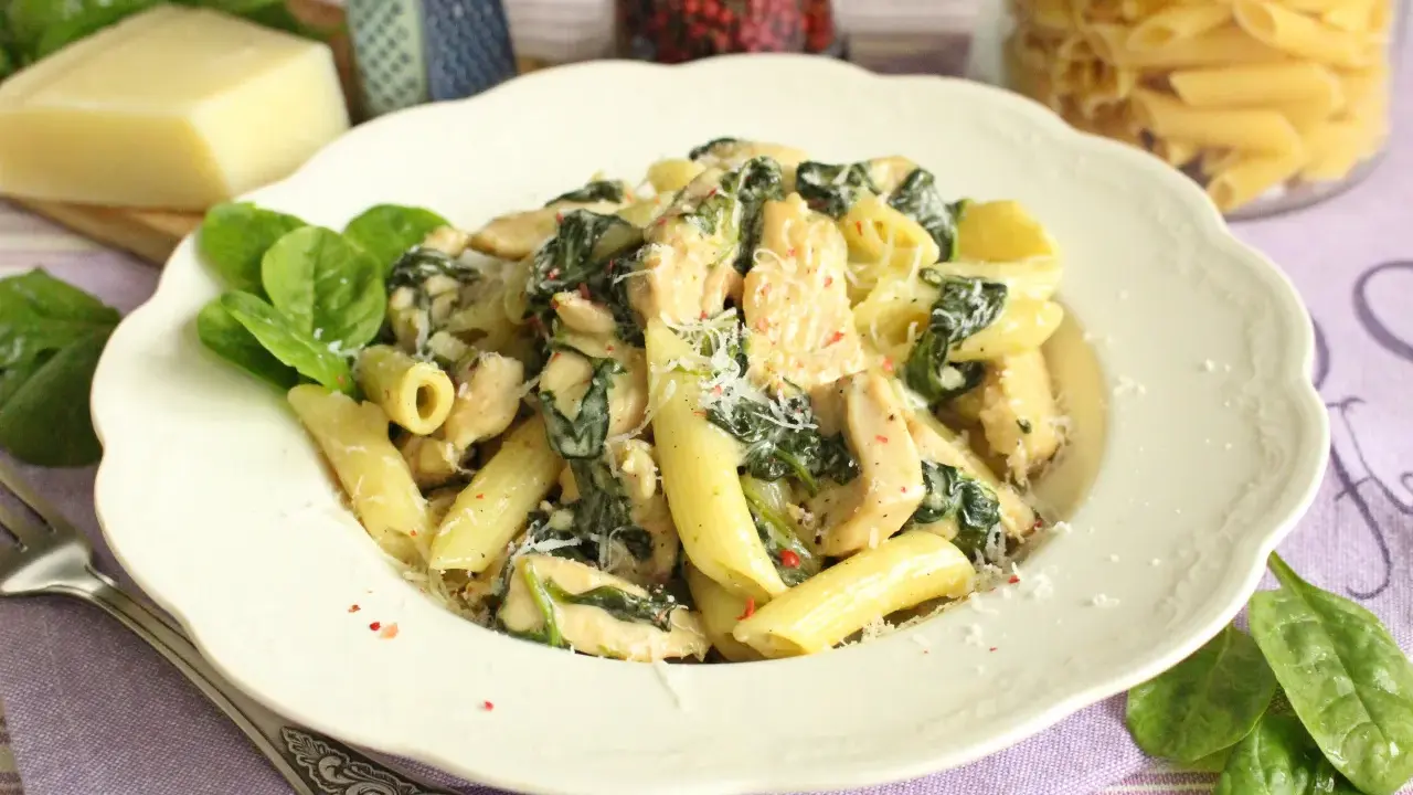 Penne z kurczakiem i szpinakiem w kremowym sosie, posypane parmezanem. Pyszne danie, które zachwyci każdego.