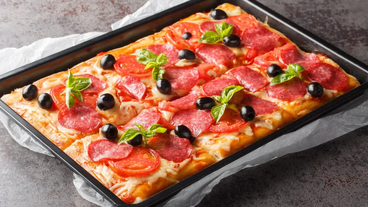 Chrupiąca pizza z ciasta francuskiego z salami, pomidorami, oliwkami i bazylią, prosto z blachy.