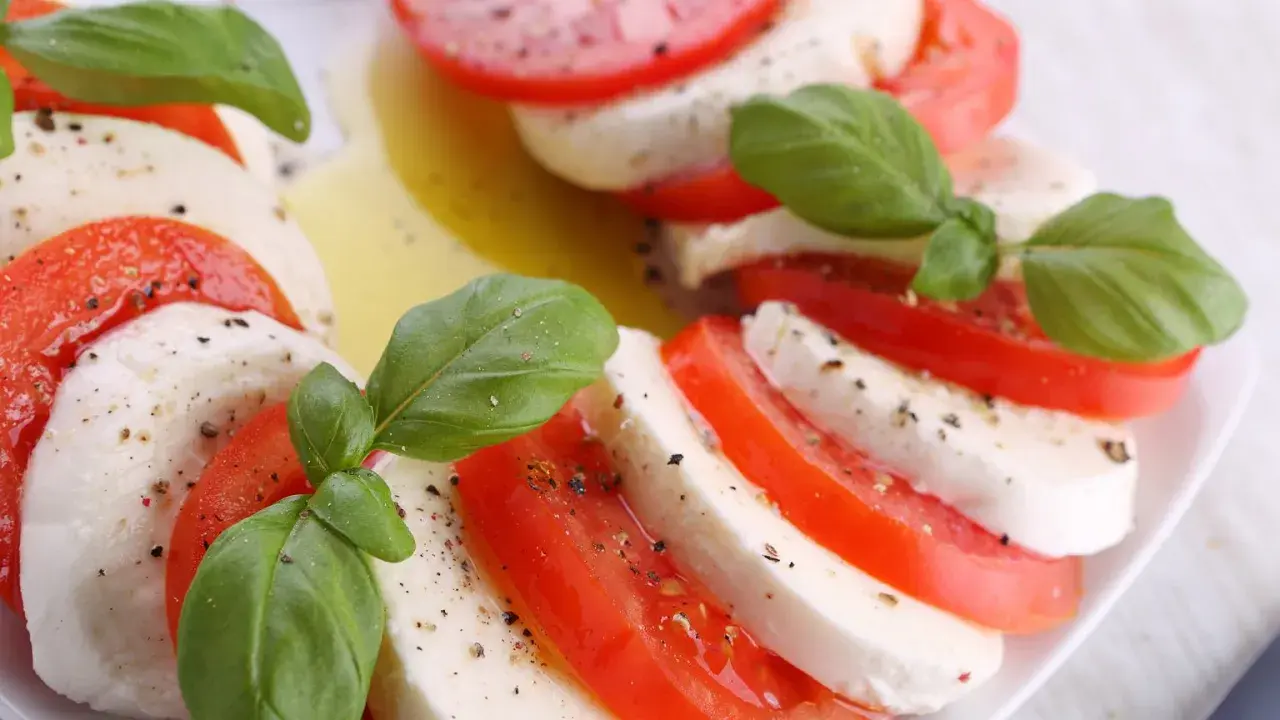 Sałatka z mozzarellą, pomidorami i bazylią, skropiona oliwą i pieprzem. Klasyczne połączenie smaków.