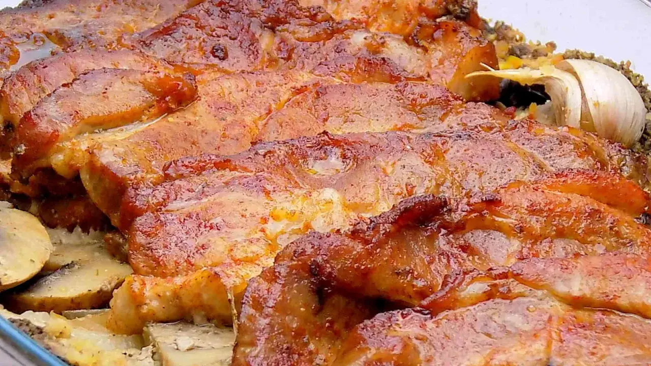 Soczysta karkówka z pieczarkami i ziemniakami, zapieczona w szklanym naczyniu. Aromatyczny czosnek dodaje głębi smaku.
