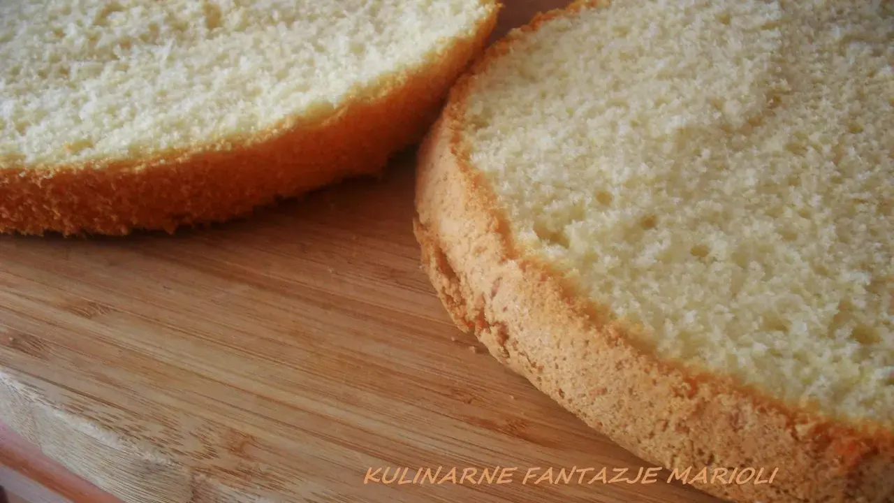 Dwa puszyste krążki biszkoptu z 4 jaj na drewnianej desce, gotowe do dekoracji.