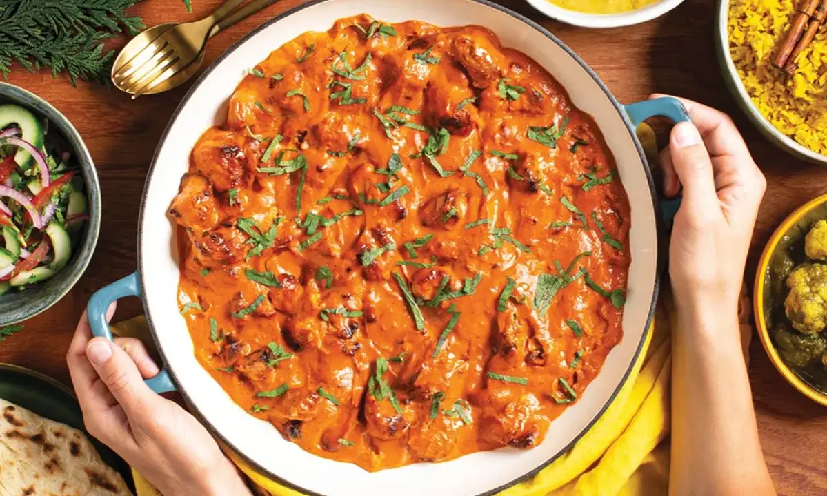 Pyszny butter chicken przepis w kremowym sosie, podany z ryżem, sałatką i chlebkiem naan.