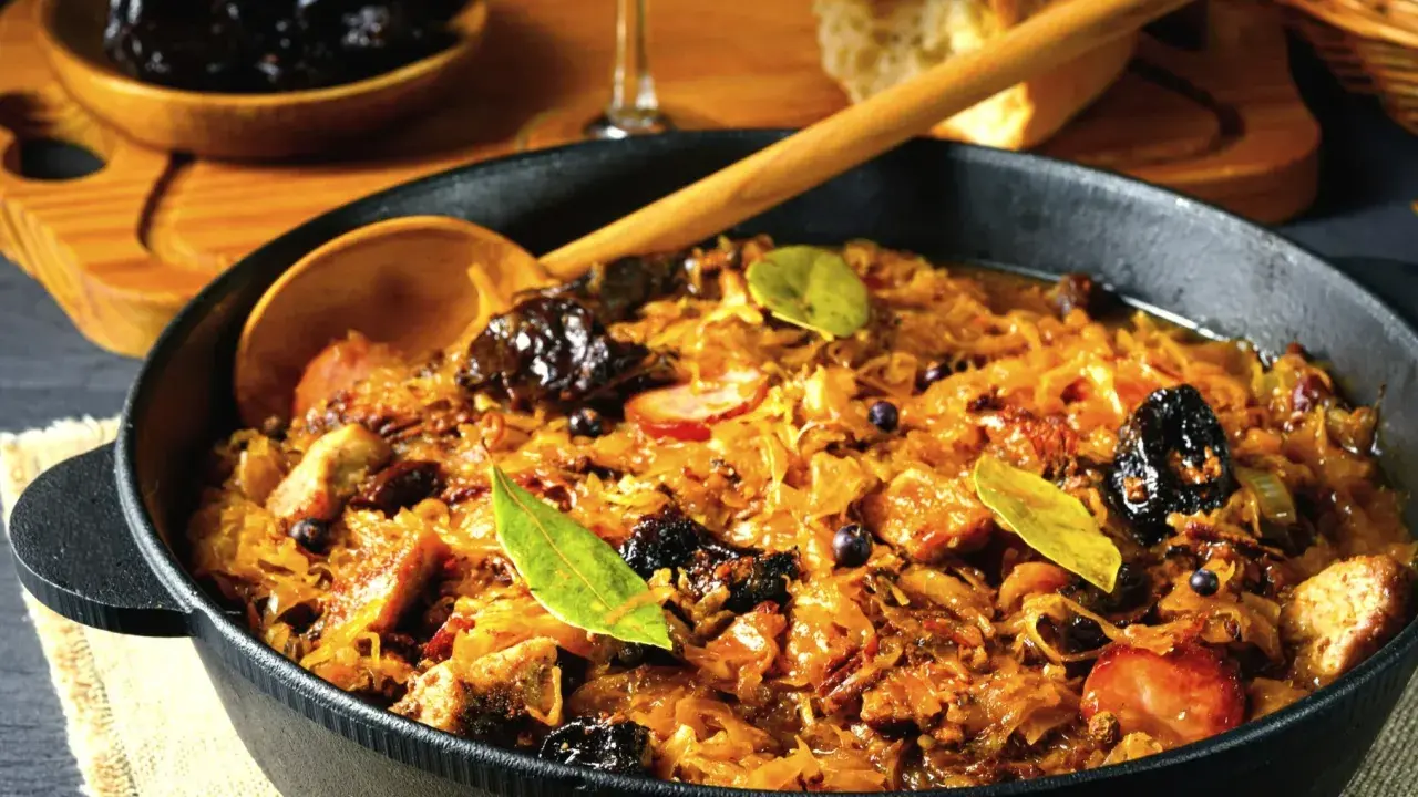 Ania gotuje pyszny bigos w żeliwnym naczyniu, pełen kapusty, mięsa i śliwek.