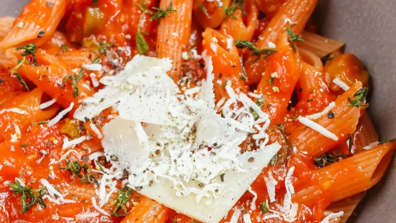 Penne w sosie pomidorowym z oliwkami i parmezanem. Idealny szybki obiad z makaronem, doprawiony ziołami.