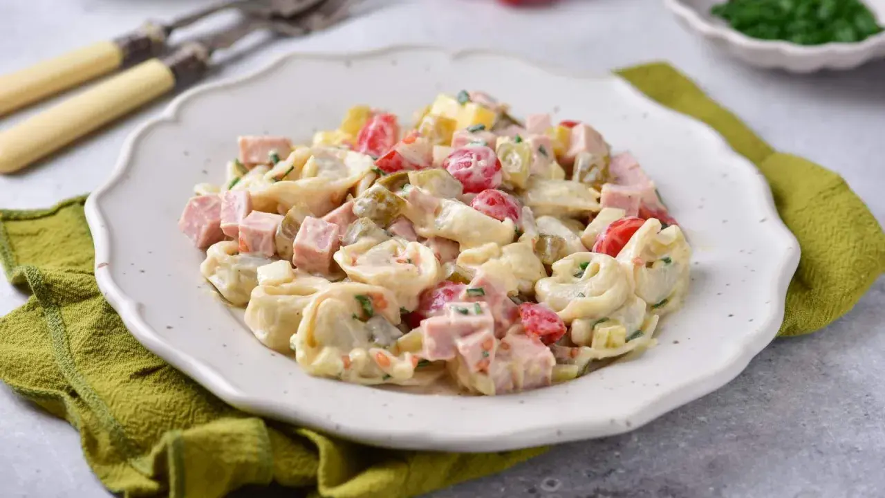 Pyszna sałatka z tortellini, szynki, pomidorków i ogórków konserwowych w kremowym sosie. Idealna na każdą okazję.
