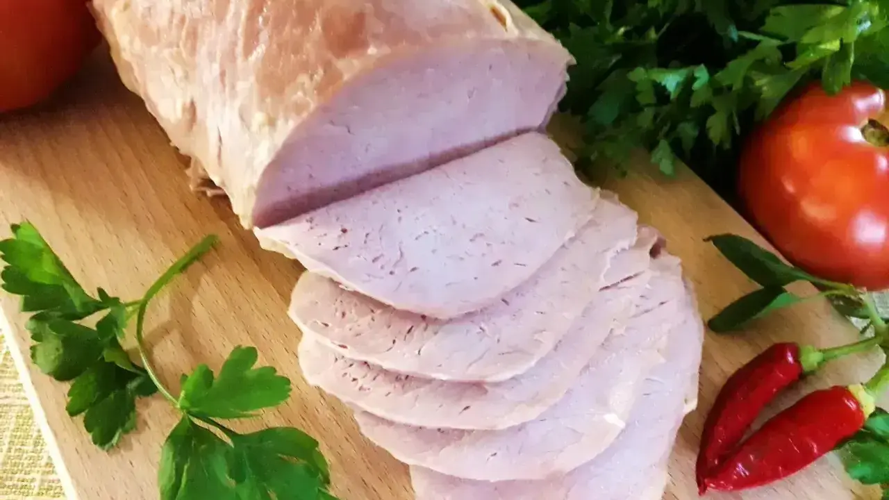 Schab gotowany 2 razy po 10 minut, pokrojony w plastry, z pomidorami i papryczkami chili na desce.