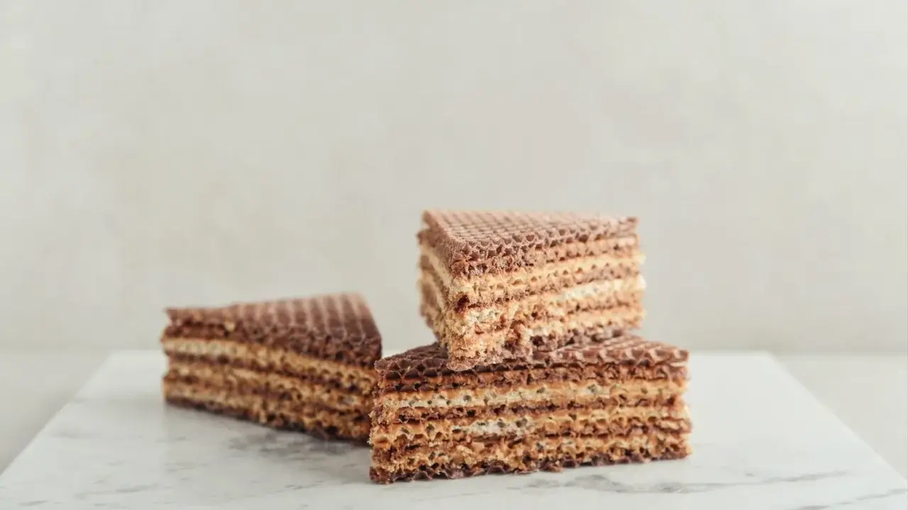 Słodkie wafle z kajmakiem, ułożone na marmurowym blacie, kuszą chrupiącą teksturą i kremowym nadzieniem.