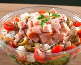Pyszna sałatka z wędzonym kurczakiem, pomidorkami koktajlowymi, oliwkami i serem feta, posypana czarnuszką.