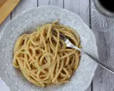 Porcja pysznego cacio e pepe z widelcem w talerzu, gotowa do zjedzenia.