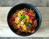 Pyszny makaron chow mein z kurczakiem, papryką i szczypiorkiem, posypany sezamem.