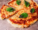 Pyszna pizza z air fryera, z ciągnącym się serem i świeżą bazylią, wygląda apetycznie na drewnianym blacie.