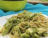Pyszny makaron z pesto i kurczakiem, podany z plasterkami cytryny.