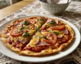 Pyszna pizza z tortilli z pomidorami, cebulą, szynką i serem, udekorowana bazylią. Idealna na szybki obiad.