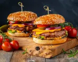 Dwa soczyste burgery z idealnie wysmażonym mięsem na burgera, serem, warzywami i sezamową bułką, podane na drewnianej desce z pomidorkami koktajlowymi.