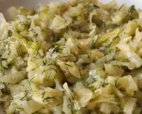 Młoda kapusta zasmażana z koperkiem, podana w białej misce. Danie wygląda na delikatne i aromatyczne.