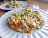Pyszne risotto z kurczakiem i kolorowymi warzywami, udekorowane listkiem bazylii. Idealne na obiad.