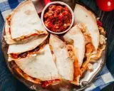 Pyszna quesadilla z kurczakiem, podana z salsą pomidorową na srebrnej tacy. Idealna na szybki posiłek.
