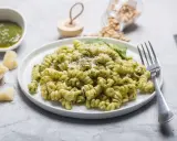 Pyszny makaron z pesto, posypany parmezanem, z dodatkiem świeżej bazylii i orzeszków piniowych.