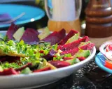 Pyszne carpaccio z buraka z awokado i świeżą natką pietruszki, doprawione pieprzem.
