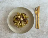 Penne z kurczakiem i suszonymi pomidorami, polane aromatycznym makaronem z pesto ze słoika, posypane parmezanem. Obok złote sztućce.