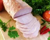 Schab gotowany 2 razy po 10 minut, pokrojony w plastry, z pomidorami i papryczkami chili na desce.