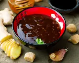 Miseczka z sosem teriyaki, obok świeży imbir, czosnek i cukier. Idealne składniki do przygotowania domowego sosu teriyaki.