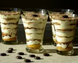 Pyszne tiramisu w pucharkach, warstwowo ułożone z kremem i biszkoptami, posypane czekoladą i kawą.
