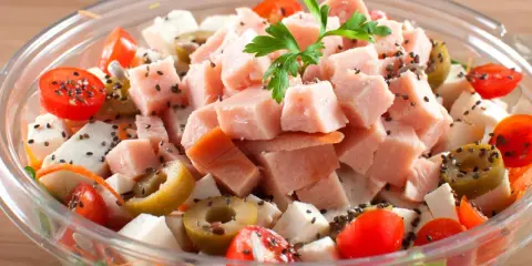 Pyszna sałatka z wędzonym kurczakiem, pomidorkami koktajlowymi, oliwkami i serem feta, posypana czarnuszką.