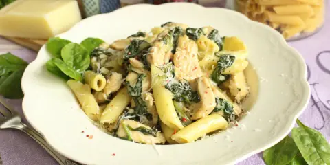 Penne z kurczakiem i szpinakiem w kremowym sosie, posypane parmezanem. Pyszne danie, które zachwyci każdego.