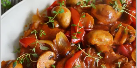 Pyszny karczek po cygańsku z pieczarkami i papryką, duszony w aromatycznym sosie, udekorowany świeżym tymiankiem.