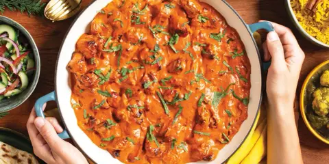 Pyszny butter chicken przepis w kremowym sosie, podany z ryżem, sałatką i chlebkiem naan.