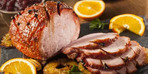 Pieczona szynka z pomarańczą i ananasem, idealna do świątecznego stołu. Marynata do szynki nadała jej piękny kolor i aromat.