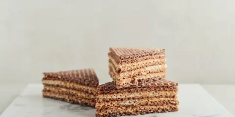 Słodkie wafle z kajmakiem, ułożone na marmurowym blacie, kuszą chrupiącą teksturą i kremowym nadzieniem.