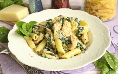 Penne z kurczakiem i szpinakiem w kremowym sosie, posypane parmezanem. Pyszne danie, które zachwyci każdego.