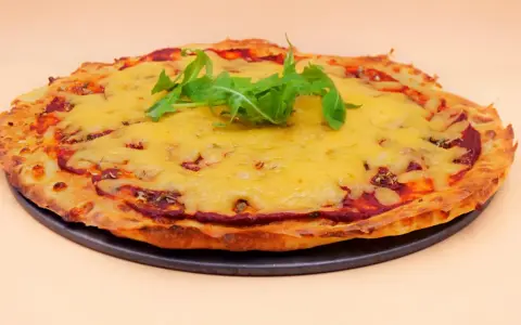Chrupiąca pizza z serka wiejskiego, pokryta ciągnącym się serem i świeżą rukolą. Idealna na szybki obiad.