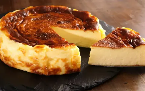 Pyszny, lekko przypieczony sernik Ani gotuje się na ciemnej desce. Jeden kawałek już czeka na spróbowanie.