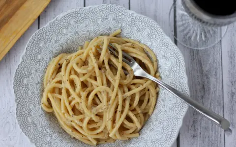 Porcja pysznego cacio e pepe z widelcem w talerzu, gotowa do zjedzenia.