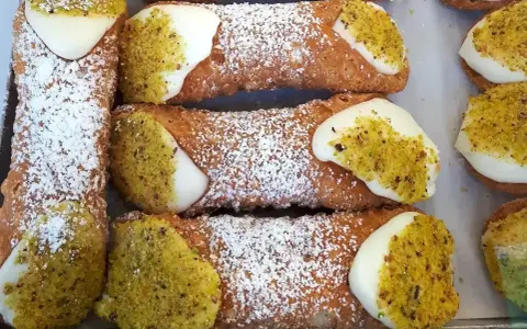 Pyszne rurki z kremem, posypane cukrem pudrem i pistacjami, kuszą swoim wyglądem.