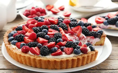 Pyszna tarta z mascarpone, udekorowana malinami, jeżynami i borówkami.