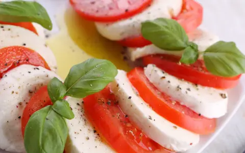 Sałatka z mozzarellą, pomidorami i bazylią, skropiona oliwą i pieprzem. Klasyczne połączenie smaków.