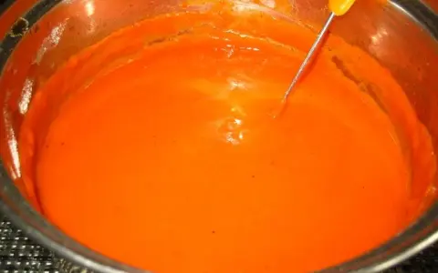 Gęsty, pomarańczowy sos pomidorowy do gołąbków w metalowym garnku, z widoczną sondą termometru.