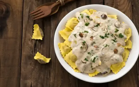Pyszne ravioli w kremowym sosie śmietanowym z grzybami i natką pietruszki. Idealny sos śmietanowy do makaronu.