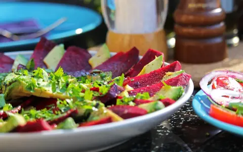 Pyszne carpaccio z buraka z awokado i świeżą natką pietruszki, doprawione pieprzem.