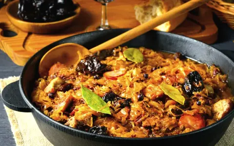 Ania gotuje pyszny bigos w żeliwnym naczyniu, pełen kapusty, mięsa i śliwek.