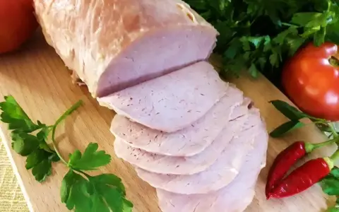 Schab gotowany 2 razy po 10 minut, pokrojony w plastry, z pomidorami i papryczkami chili na desce.