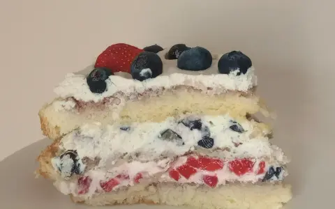 Pyszne ciasto na biszkopcie z bitą śmietaną, truskawkami i borówkami. Idealne na letnie popołudnie.