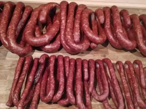 Dwie linie świeżo uwędzonej, prawdziwej wiejskiej kiełbasy, gotowe do podania. Przepis na domową kiełbasę jest w zasięgu ręki!