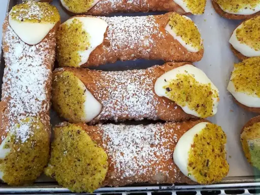 Pyszne rurki z kremem, posypane cukrem pudrem i pistacjami, kuszą swoim wyglądem.
