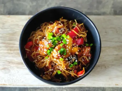 Pyszny makaron chow mein z kurczakiem, papryką i szczypiorkiem, posypany sezamem.